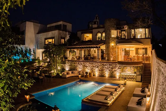 Fachada nocturna de un hotel boutique con alberca